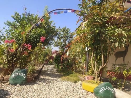 a garden with flowers and trees and a fence at Busy Bee Guest House in Sauraha