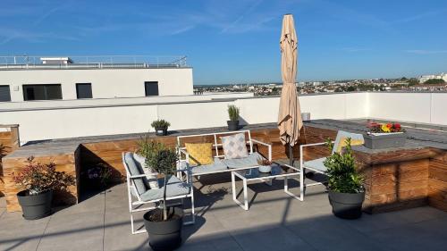 d'une terrasse avec un parasol et des chaises sur le toit. dans l'établissement Apparentement proche Paris avec terrasse vue dégagée, à Bezons