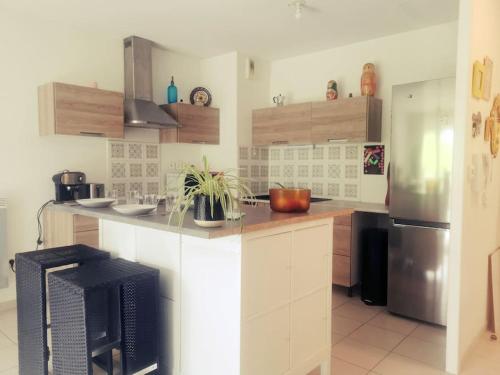 une cuisine avec des armoires blanches et un réfrigérateur en acier inoxydable dans l'établissement Belharra Appartement, à Bayonne