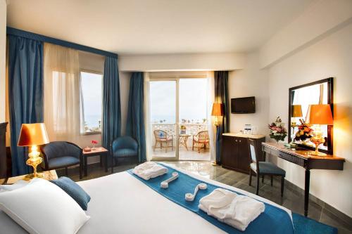 um quarto de hotel com uma cama grande, uma secretária e cadeiras em White Valley Palace em Hurghada