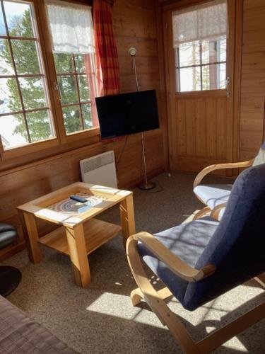 sala de estar con mesa y TV en Chalet Balfrin Alpweg 9 Postfach 2038 Riederalp, en Riederalp