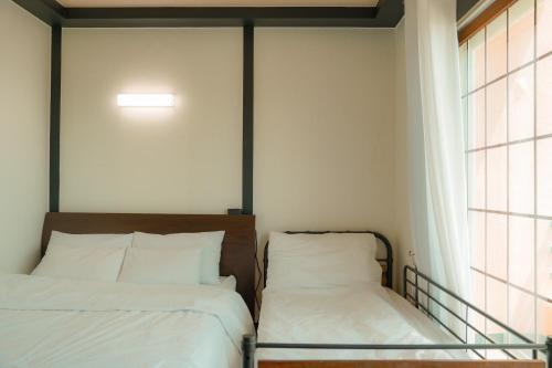a bedroom with two beds and a window at ttottot Jeju Backpackers in Seogwipo