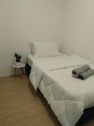 a bedroom with two beds with white sheets and a table at ITCC Manhattan Suites by Kansayan Homestay in Penampang