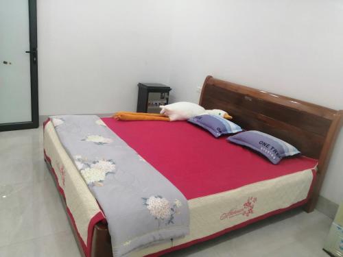 a bed with a red blanket and pillows on it at Phòng nghỉ nhà Thiên Lý in Dien Bien Phu