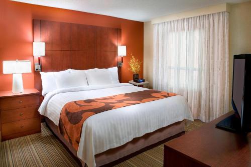 a hotel room with a bed and a flat screen tv at Residence Inn by Marriott Calgary Airport in Calgary