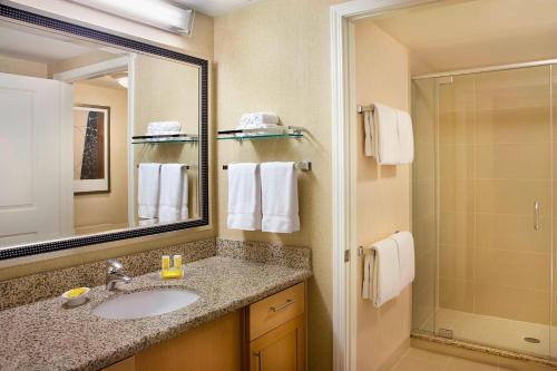 a bathroom with a sink and a mirror and a shower at Residence Inn by Marriott Calgary Airport in Calgary