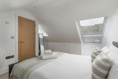 a bedroom with a large white bed with a window at Marazion Charming Retreat for 6 with Social Garden in Marazion