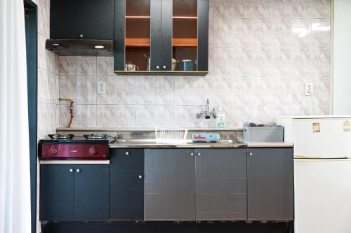 a kitchen with black cabinets and a red stove at ttottot Jeju Backpackers in Seogwipo