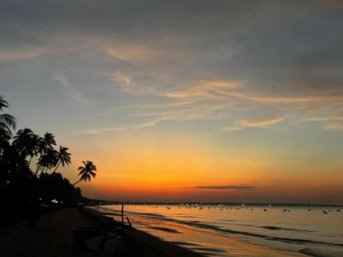 a sunset on a beach with palm trees and the ocean at Bstudio in APEC Mandala Mũi Né in Phan Thiet