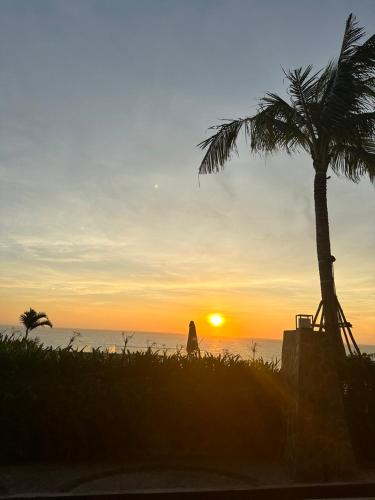 a palm tree and a person walking on the beach at sunset at Bstudio in APEC Mandala Mũi Né in Phan Thiet