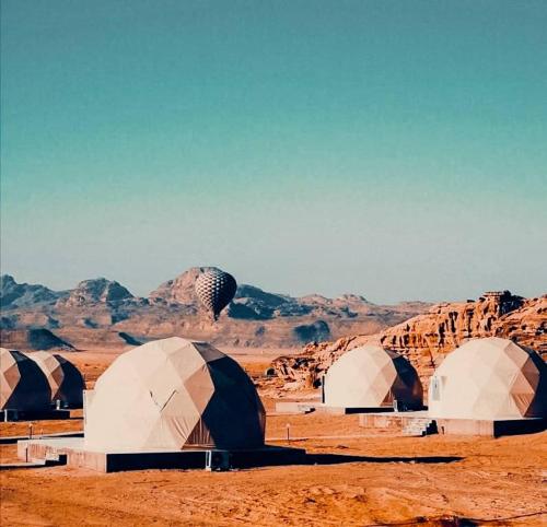 un groupe de dômes dans un désert avec des montagnes dans l'établissement wadi rum camp stars & jeep tour, à Wadi Rum