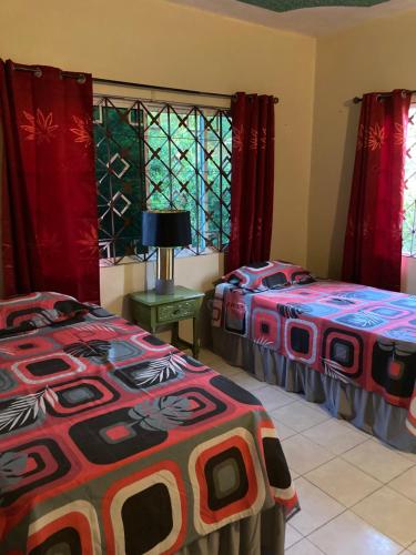two beds in a room with red curtains at Serenity II in Green Island