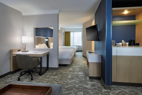 a hotel room with a bed and a desk at SpringHill Suites Detroit Southfield in Southfield