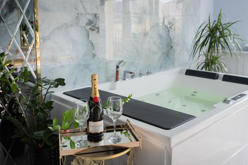 a bathroom with a tub with a bottle of champagne and glasses at Apartament Jacuzzi in Gdynia