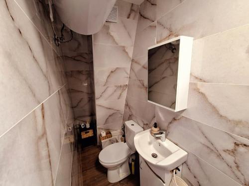 a white bathroom with a sink and a toilet at Апартамент БОХО Приморско in Primorsko