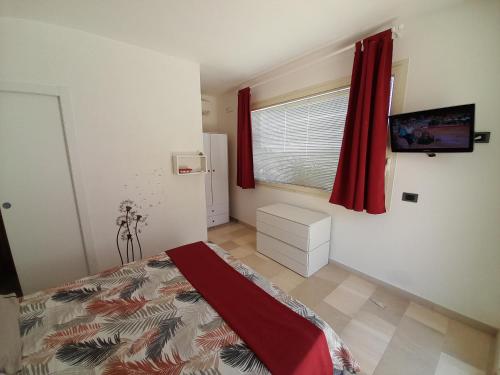 1 dormitorio con 1 cama y una ventana con cortinas rojas en Otranto d'Amare, en Casamassella