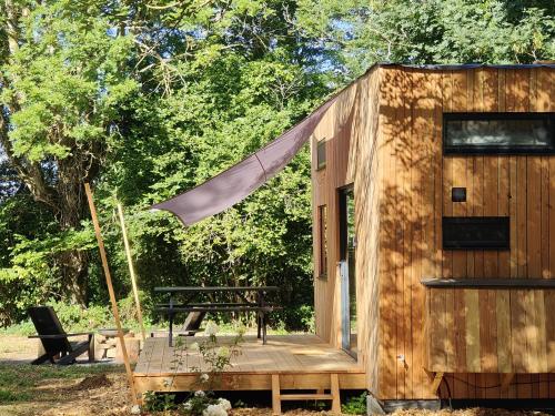 a small wooden cabin with a table and a bench at Moose home Tiny house AMBUR in Saint-Jacques-dʼAmbur