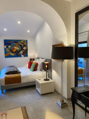 een slaapkamer met een bed, een lamp en een spiegel bij La RENAUDIERE in LʼIsle-sur-la-Sorgue