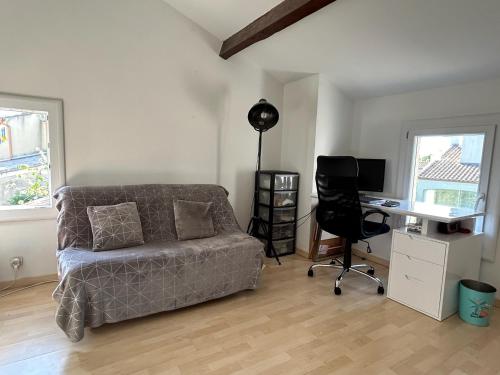 - un salon avec un canapé et un bureau avec un ordinateur dans l'établissement Maison au calme arborée, à Mauguio