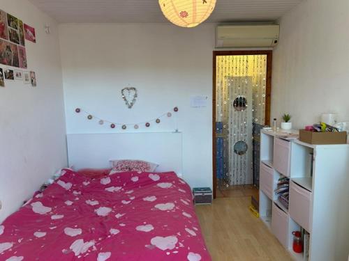 une chambre avec un lit avec un couvre-lit rouge avec des cœurs dessus dans l'établissement Maison au calme arborée, à Mauguio