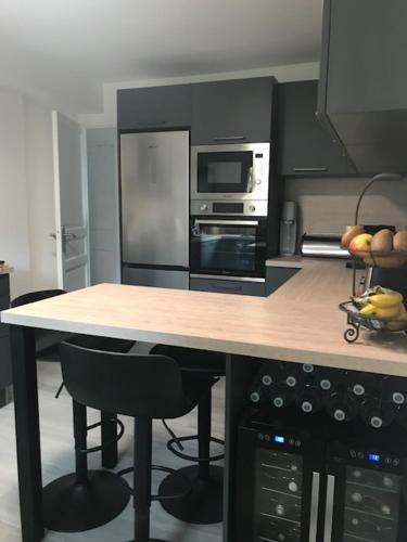 une cuisine avec un comptoir, un four micro-ondes et une table avec des chaises dans l'établissement Maison au calme arborée, à Mauguio