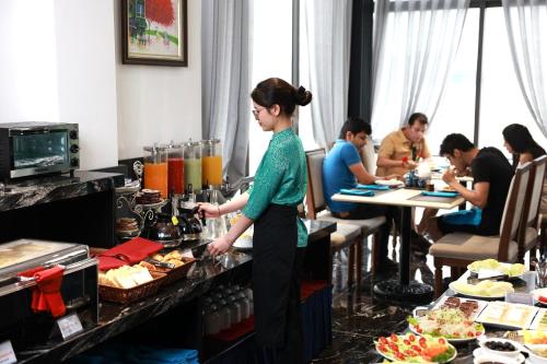 a woman standing at a buffet in a restaurant at Hanoi Dalvostro Valentino Hotel & Spa in Hanoi