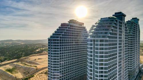 two tall buildings with the sun shining on them at Bstudio in APEC Mandala Mũi Né in Phan Thiet