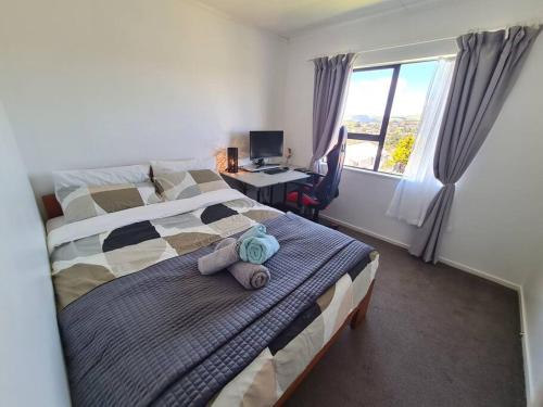 a bedroom with a bed and a desk with a computer at Hilltop Blue Sky House in Porirua