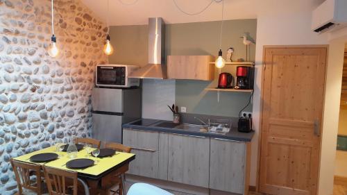 une cuisine avec une table avec des chaises et un micro-ondes dans l'établissement gite du lavoir, à Meximieux