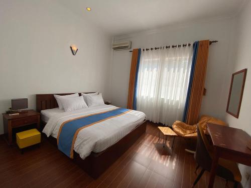 a bedroom with a large bed and a desk and a desk at Maha Kali Hotel in Phumi Ta Phul