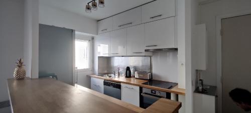 een keuken met witte kasten en een houten aanrecht bij Appartement Cosy Suresnes in Suresnes