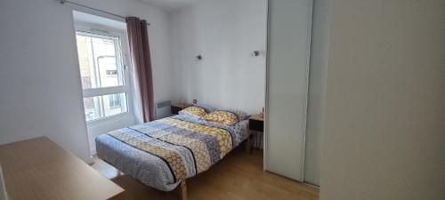 een kleine slaapkamer met een bed en een raam bij Appartement Cosy Suresnes in Suresnes