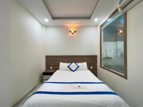 a bedroom with a white bed with a blue pillow at Khách Sạn TRẦN LONG in Ho Chi Minh City