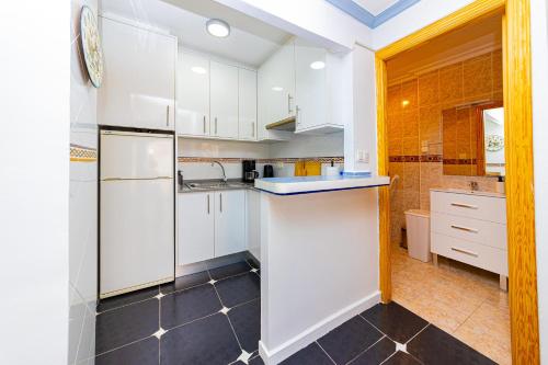 a kitchen with white cabinets and a black tile floor at Puerto Romano 21 in La Mata