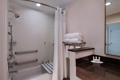 a bathroom with a shower and a sink with towels at Fairfield by Marriott Inn & Suites Waller in Waller