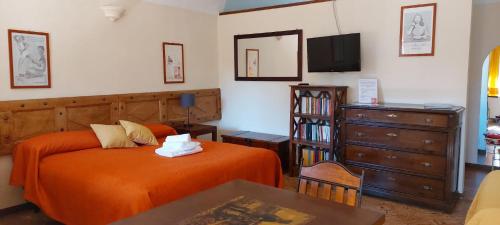 a bedroom with an orange bed and a dresser at Oryza Guest House in Desana