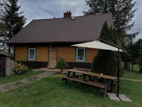 - une table de pique-nique avec un parasol en face d'une maison dans l'établissement Domek na wsi Wiejsko Czarodziejsko - Agroturystyka Podlasie, 