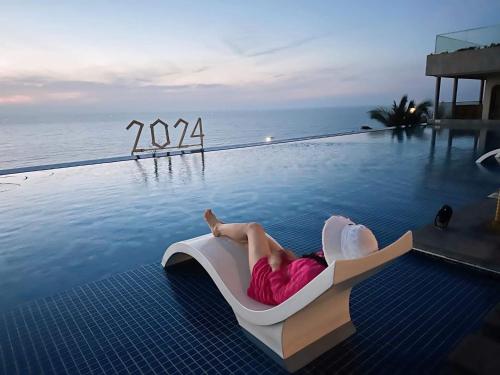 a woman laying on a chair next to a swimming pool at Bstudio in APEC Mandala Mũi Né in Phan Thiet