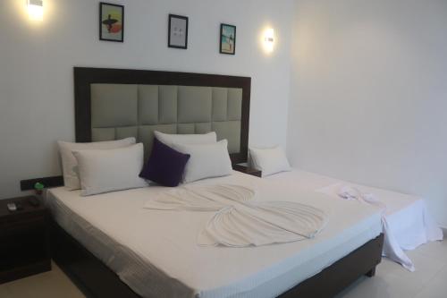 a bedroom with a large bed with white sheets and pillows at Mzion Hotel Weligama in Weligama