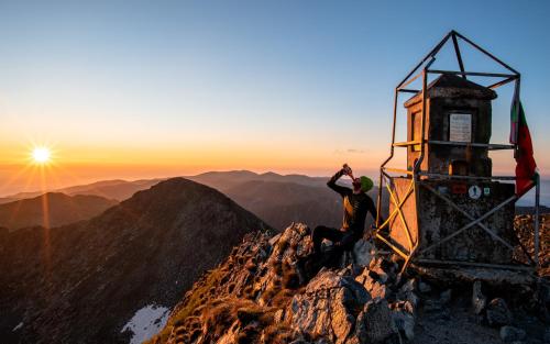 a man sitting on the top of a mountain at Cozy Mountain Apartment in Borovets