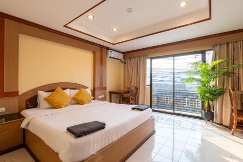 a bedroom with a large bed and a large window at La Casa South Pattaya Hotel in Pattaya South