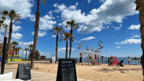 a beach with palm trees and a playground at Puerto Romano 21 in La Mata