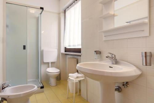 Baño blanco con lavabo y aseo en Residence il Cedro, en Malcesine
