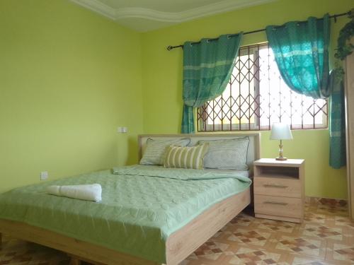a bedroom with a bed and a window with blue curtains at Kim's Guest House in Kasoa