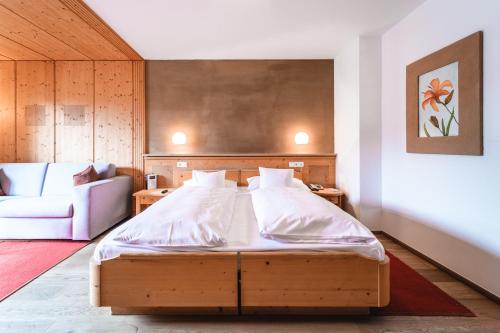 a bedroom with a bed and a couch at Naturhotel Leitlhof in San Candido