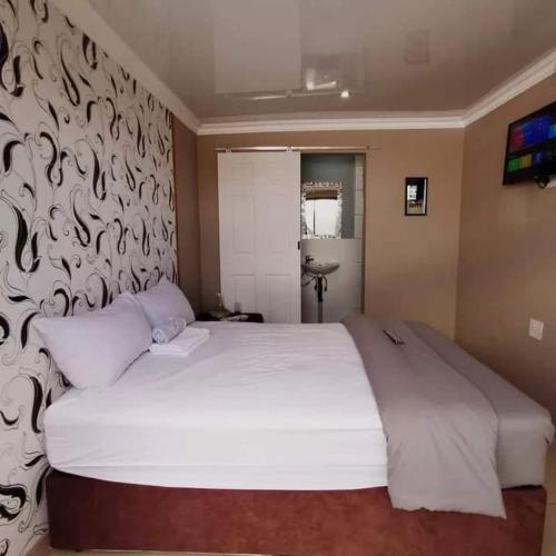 sypialnia z dużym białym łóżkiem ze wzorzystą ścianą w obiekcie 54inn w mieście Dube