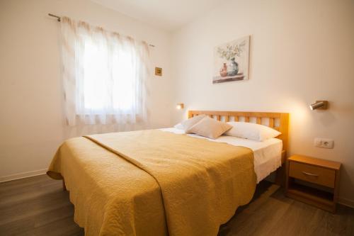 - une chambre avec un lit doté d'une couverture jaune et d'une fenêtre dans l'établissement Sirius Apartments, à Bol