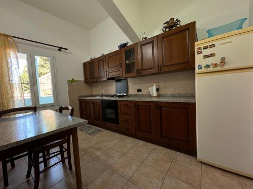 Una cocina con gabinetes de madera y un refrigerador blanco. en PM 12 Via Umberto Primo Guest House, en Torpè
