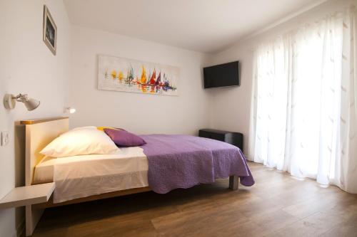 - une chambre avec un lit et une couverture violette dans l'établissement Sirius Apartments, à Bol