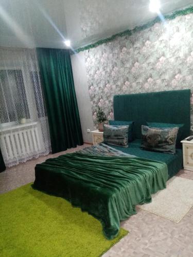 ein Schlafzimmer mit einem grünen Bett und einer grünen Decke in der Unterkunft Всегда рады гостям центр города in Oral